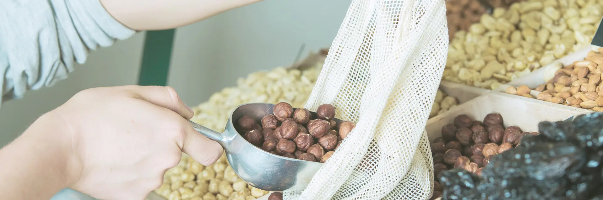 someone refilling reusable bag with produce (nuts & dates)
