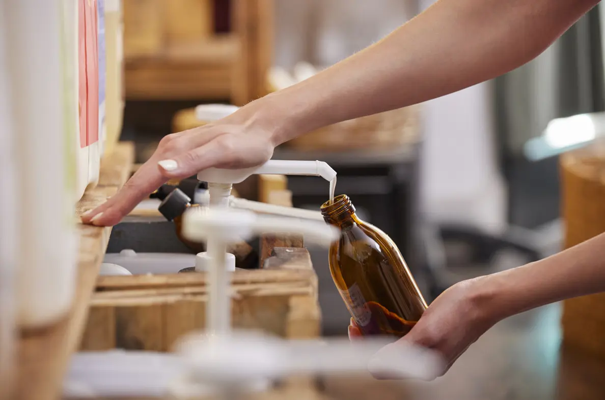 Someone refilling refillable bottle with pump of product