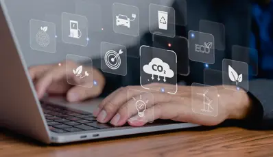  Hands using a laptop with sustainability and climate icons on the screen.