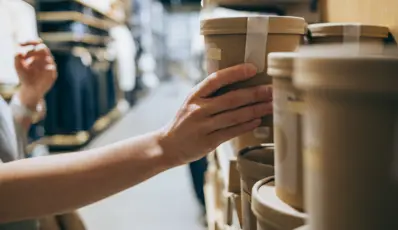 Someone's hand grabbing sustainably packaged product off the shelf