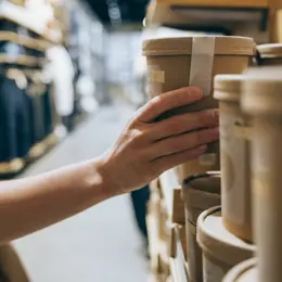 Someone's hand grabbing sustainably packaged product off the shelf