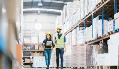 Two people in PPE walking through warehouse
